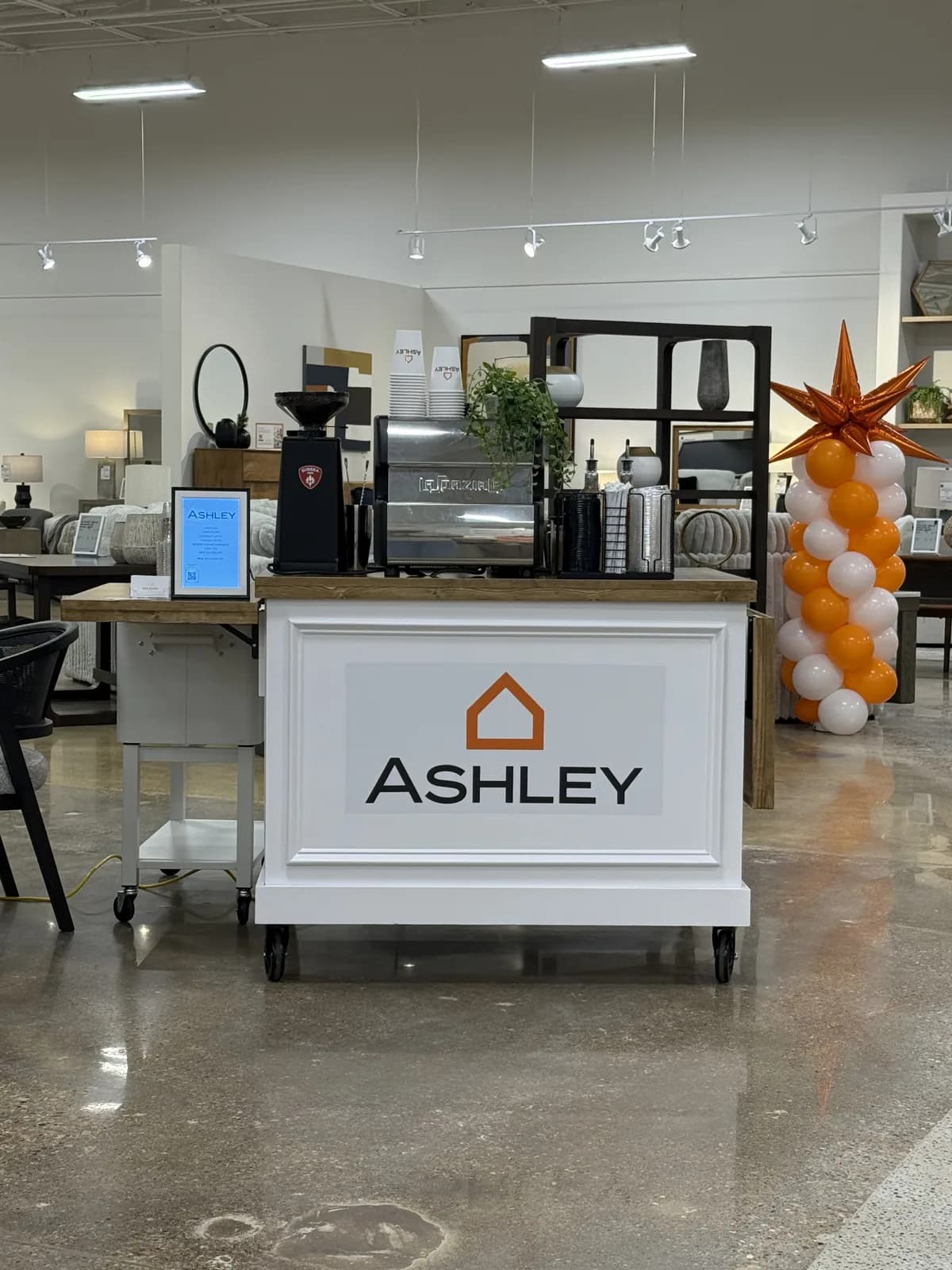 Enlightened Café espresso cart custom-branded with the Ashley logo, with Ashley-printed cups, at a DFW showroom event