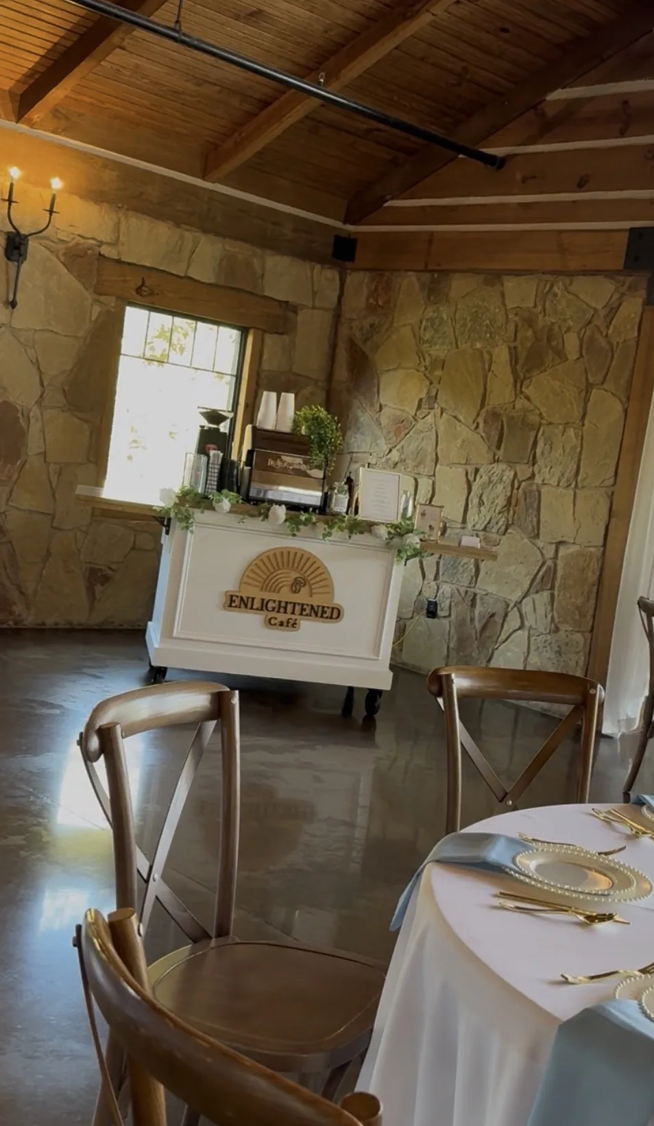 Enlightened Café mobile coffee cart dressed with greenery at a stone-and-timber wedding venue in Dallas–Fort Worth